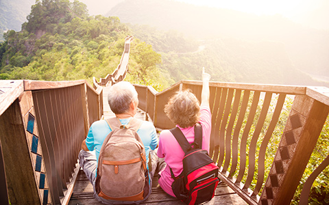 senior couple sitting on a bridge overlooking beautiful scenery