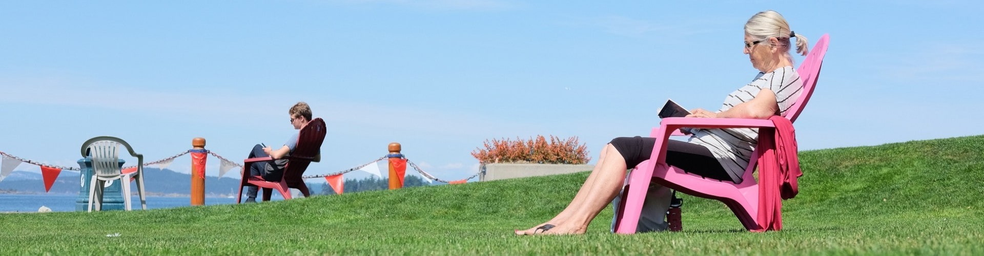 senior woman sitting on a chair on grass overlooking the ocean